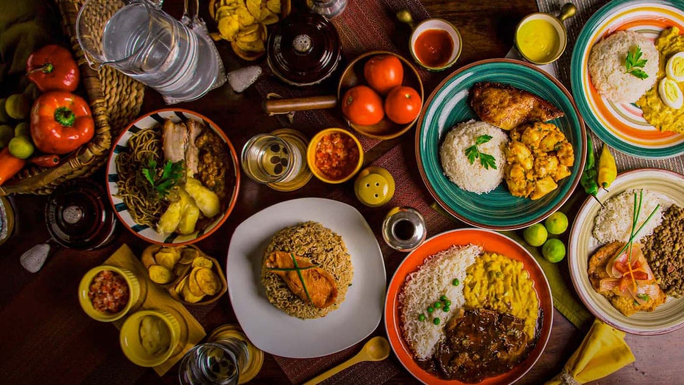 Overhead view of a table set with plates of rice, stews, sauces, and fresh produce